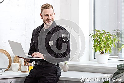 handsome policeman smiling and using laptop Stock Photo