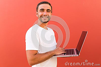 Handsome programmer man with laptop on red background Stock Photo