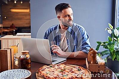 Handsome programmer with pizza and laptop Stock Photo