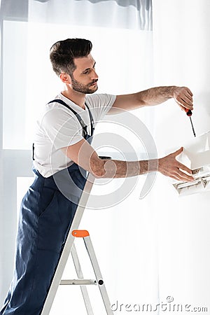 Handsome repairman standing on stepladder and Stock Photo