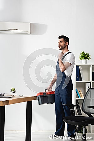 Handsome repairman standing with toolbox near Stock Photo