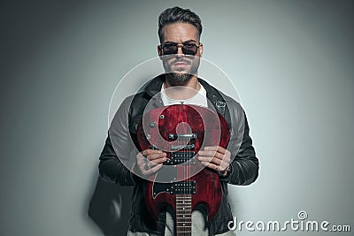 Handsome rock singer holding his electric guitar upside down Stock Photo