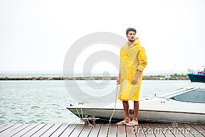 Handsome sailor in yellow cloak standing at the pier Stock Photo