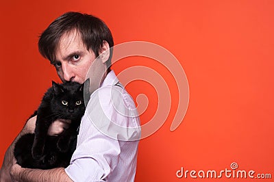 Handsome serious man, looking at camera, holding and kissing black cat Stock Photo