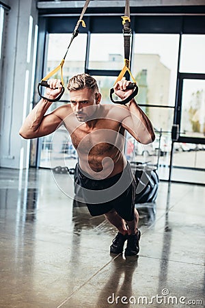 handsome shirtless sportsman exercising with resistance bands Stock Photo