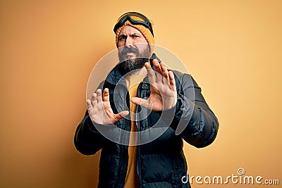 Handsome skier bald man with beard skiing wearing snow sportswear and ski goggles disgusted expression, displeased and fearful Stock Photo