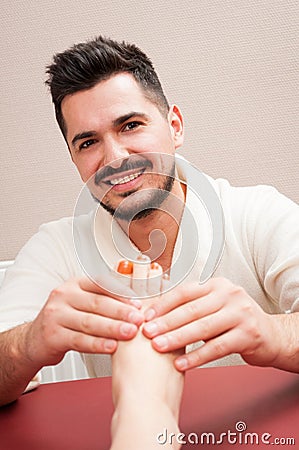 Handsome smiling masseur massaging young female feet Stock Photo