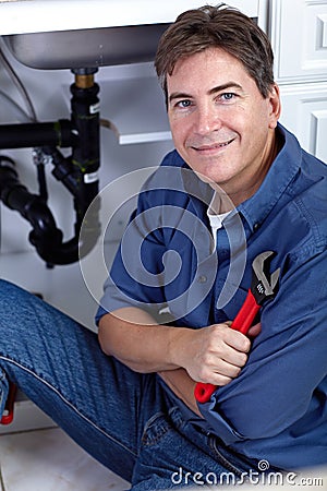 Smiling plumber repairs a sink. Stock Photo