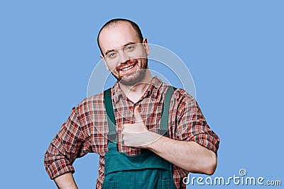 Handsome smiling workman looking at camera isolated on blue, Stock Photo