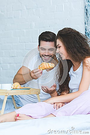 handsome smiling young man feeding beautiful girlfriend Stock Photo