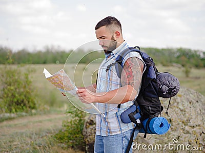 Strong bearded hiking guide looking at the map on a natural background. Hiking concept. Copy space. Stock Photo