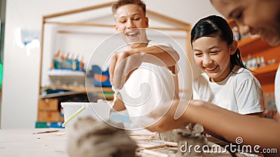 Handsome student dipping hand in to water to soften clay at class. Edification. Stock Photo