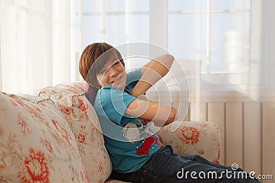 Handsome teenage boy sittin on a sofa and making faces Stock Photo