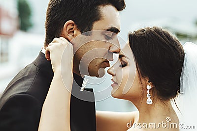 Handsome tender groom romanticaly kissing brunette beautiful bride Stock Photo