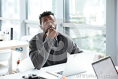 Handsome thinking serious young man sitting in office coworking Stock Photo