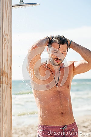 Handsome topless man taking a shower on the beach Stock Photo