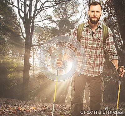 Handsome traveler with hiking poles in autumnal forest Stock Photo