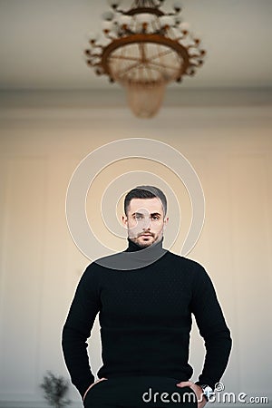 Handsome trendy man in stylish clothing outfit over classic modern interior. Stock Photo