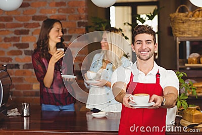 Handsome waiter handing a cup of coffee Stock Photo