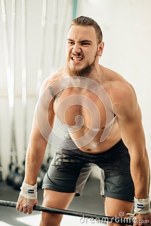 Young man weightlifter preparing for training with barbells at gym. CrossFit. Stock Photo