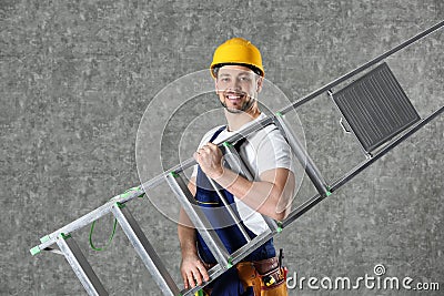 Handsome working man in hard hat holding ladder against color Stock Photo