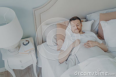 Handsome young bearded man sleeping in spacious comfortable bed Stock Photo