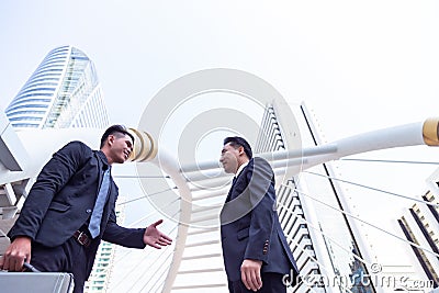 Handsome young businessman is introducing his self to elder businessman or customer by giving his hand to him at appointment Stock Photo