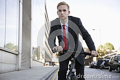 Handsome young businessman riding bicycle on street Stock Photo