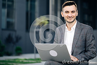 Handsome young businessman sitting outdoors working with his laptop. Crisis 2020. Distance working. Isolated man in a Stock Photo