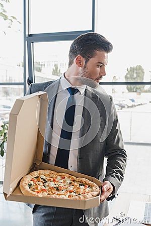 handsome young businessman in suit holding box with pizza Stock Photo