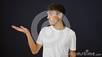 Handsome young hispanic man presenting with all seriousness, a stark portrait of raw expression isolated against a black Stock Photo