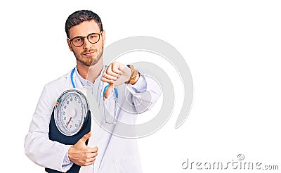 Handsome young man with bear as nutritionist doctor holding weighing machine with angry face, negative sign showing dislike with Stock Photo