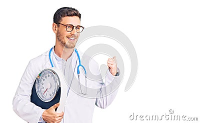 Handsome young man with bear as nutritionist doctor holding weighing machine pointing thumb up to the side smiling happy with open Stock Photo