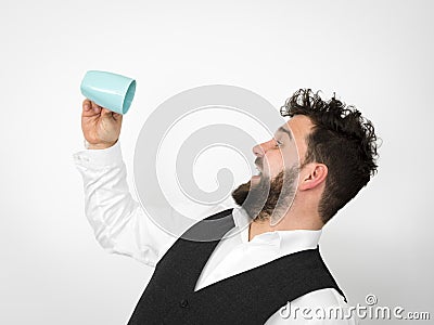 Handsome, young man with black beard posing with turquoise coffee cup or tea cup in front of white background Stock Photo