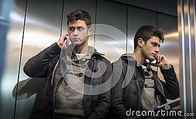 Handsome young man in elevator (lift) using cell phone Stock Photo