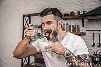 Handsome young man is having his breakfast cereal with milk. he is enjoying breakfast smiling Stock Photo