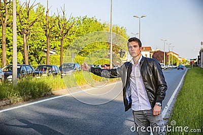Handsome young man, hitchhiker waiting on roadside Stock Photo