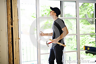 A handsome young man installing Double Sliding Patio Door in a new house construction site Stock Photo