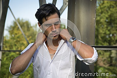 Handsome young man leaning against metal electricity trellis Stock Photo