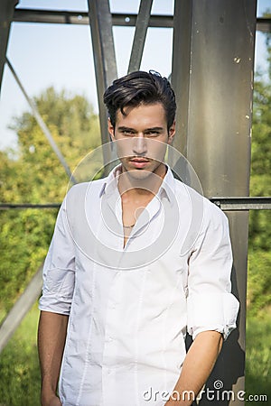 Handsome young man leaning against metal electricity trellis Stock Photo