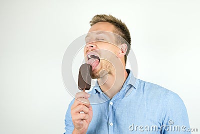 Handsome young man licking chololate ice-cream on isolated white background Stock Photo