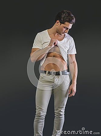 Handsome young man pulling up t-shirt, showing abs Stock Photo