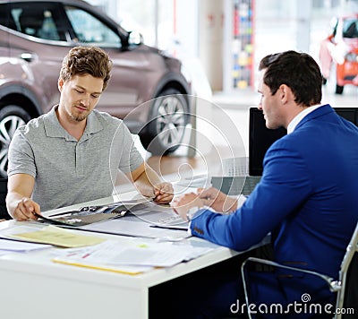 Handsome young man reading a booklet at the dealership showroom. Stock Photo