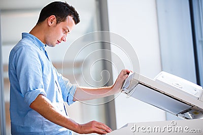 Handsome young man using a copy machine Stock Photo