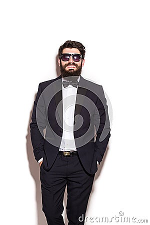 Handsome young man wearing suit and glasses keeping hands in pockets and looking at camera Stock Photo