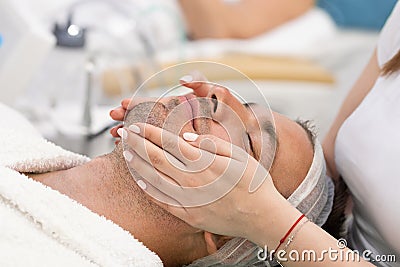 Young handsome man receiving facial massage and spa treatment Stock Photo