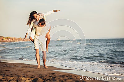Young man giving piggyback ride to girlfriend on beach. Young couple enjoying summer holidays Stock Photo