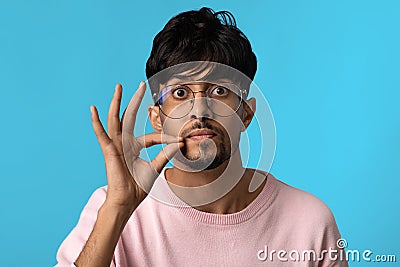 Handsome young middle eastern guy showing mouth zipped gesture Stock Photo