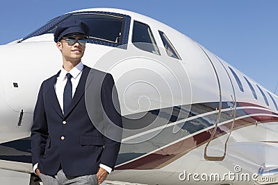 Handsome young pilot standing by private airplane Stock Photo