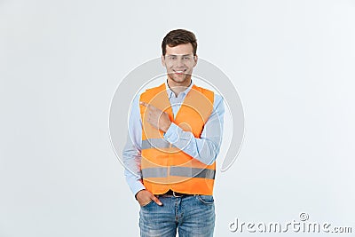 Handsome young professional engineer man over grey wall wearing orange vest amazed and surprised looking and pointing Stock Photo